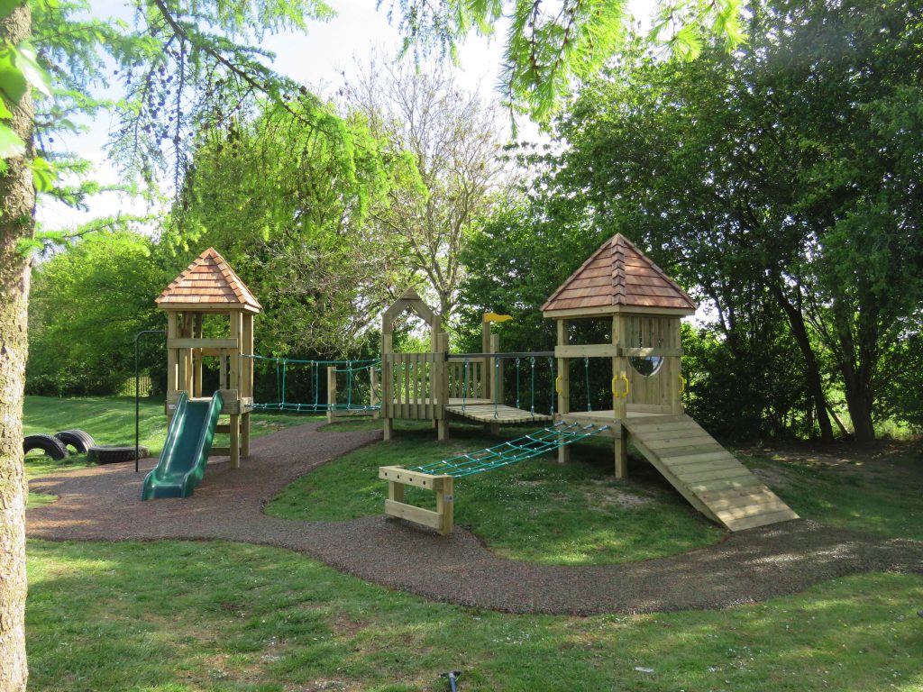 Wooden play towers connected by bridges and rope nets with slides
