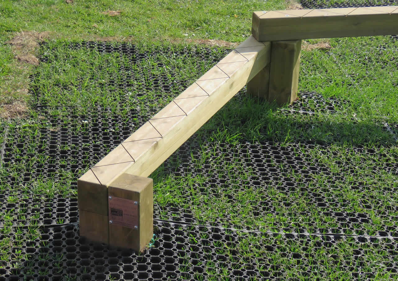 A zig zag wooden bench over grass mat tiles