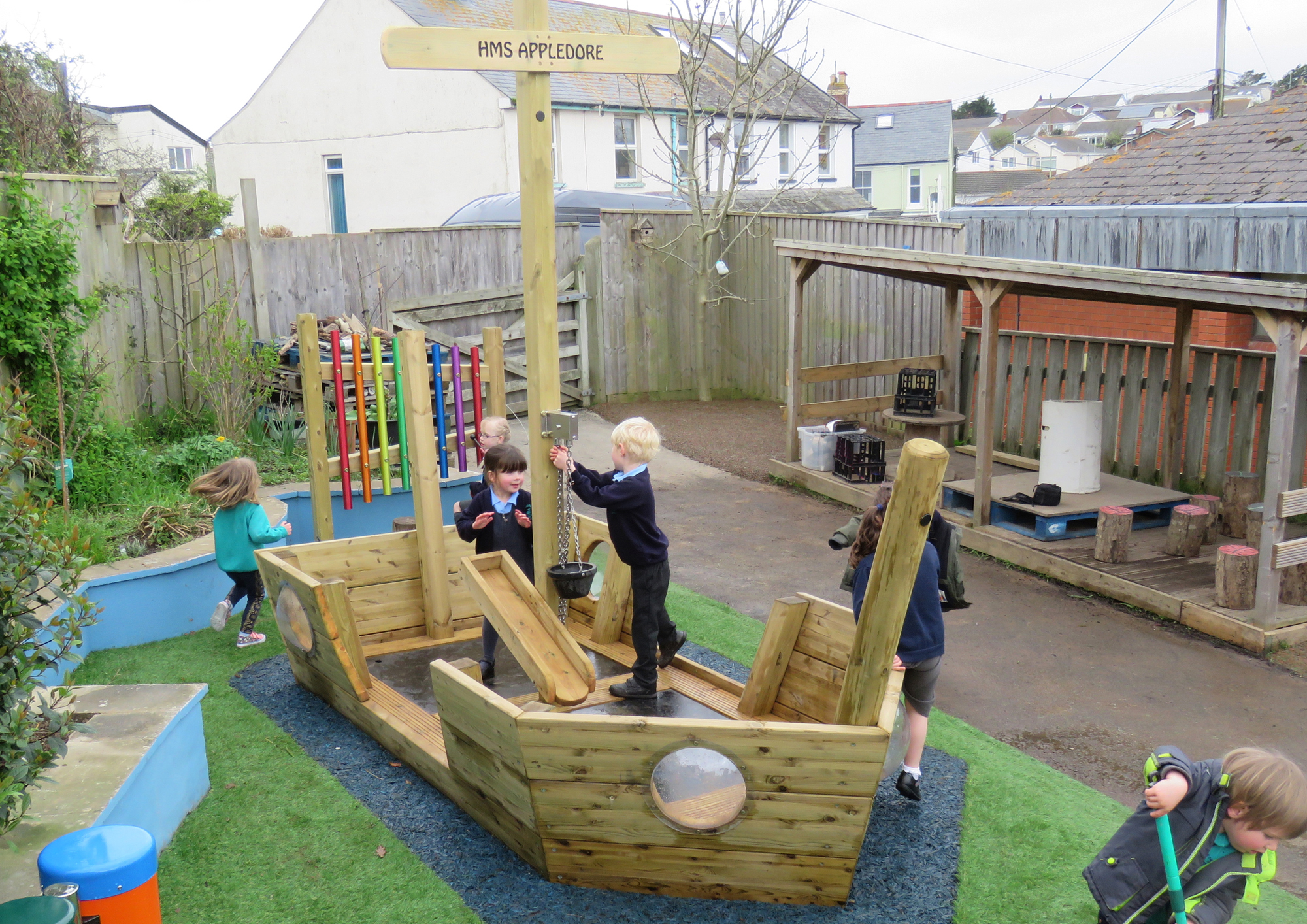 Children playing on a wooden play boat in a school playground