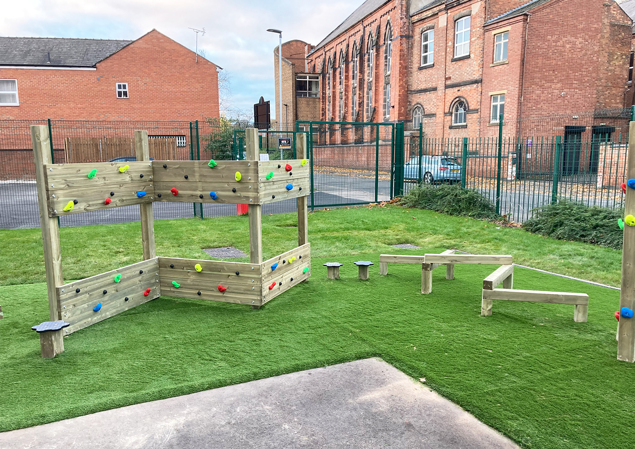 A school play area with zig zag wooden climber and climbing poles