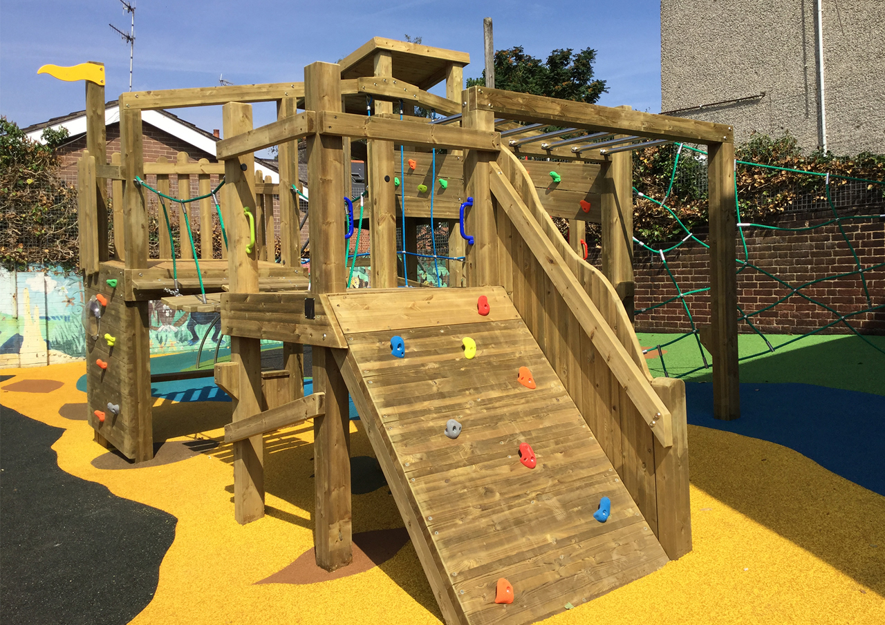 A wooden play climbing ramp installed on safety surfacing