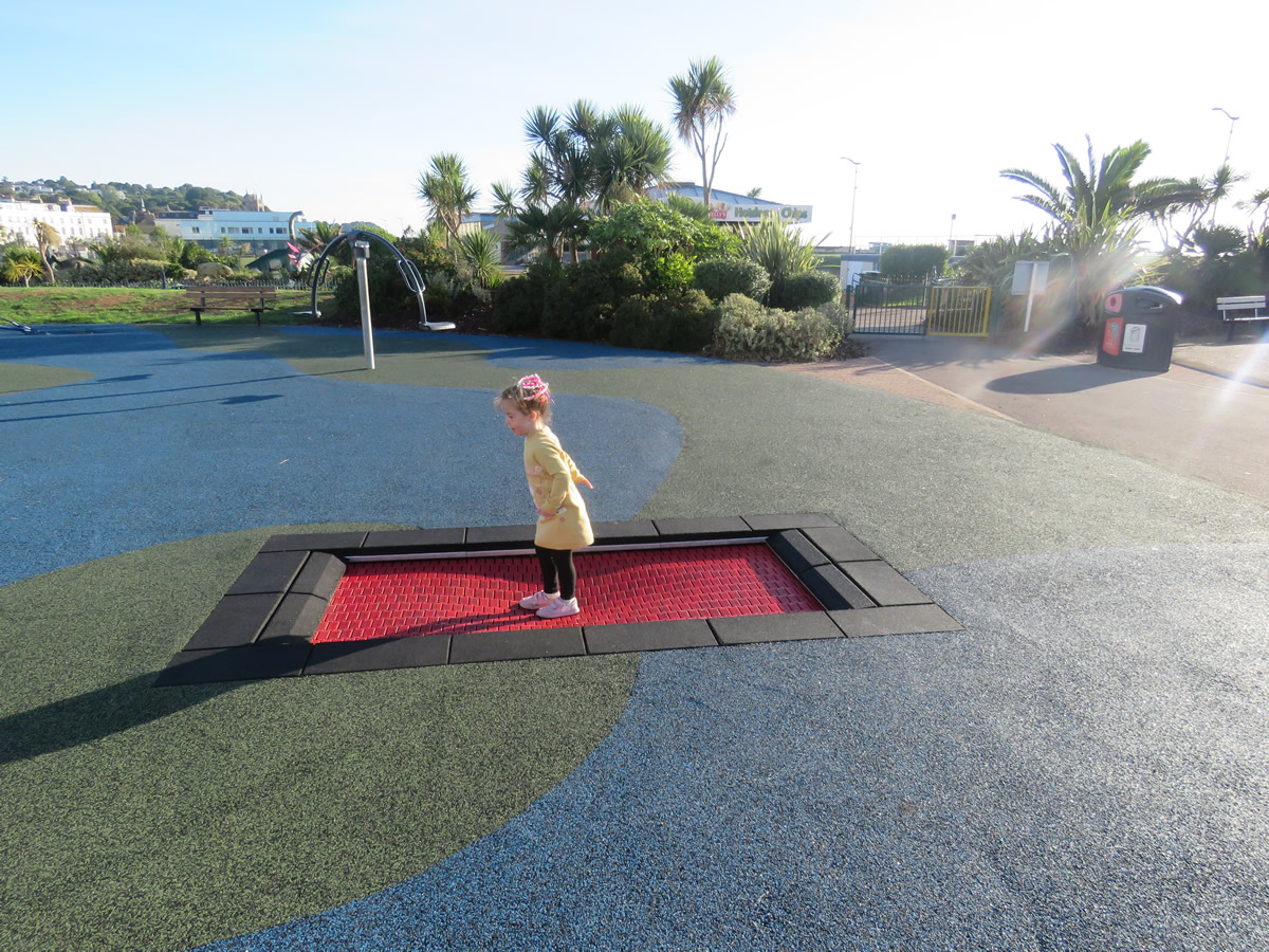 A playground trampoline with safety surfacing