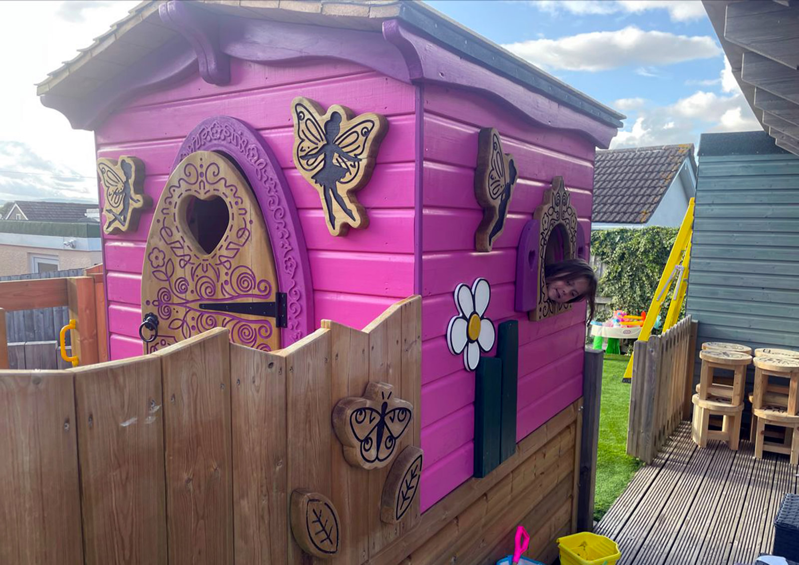 A pretty pink play house with fencing and arched door